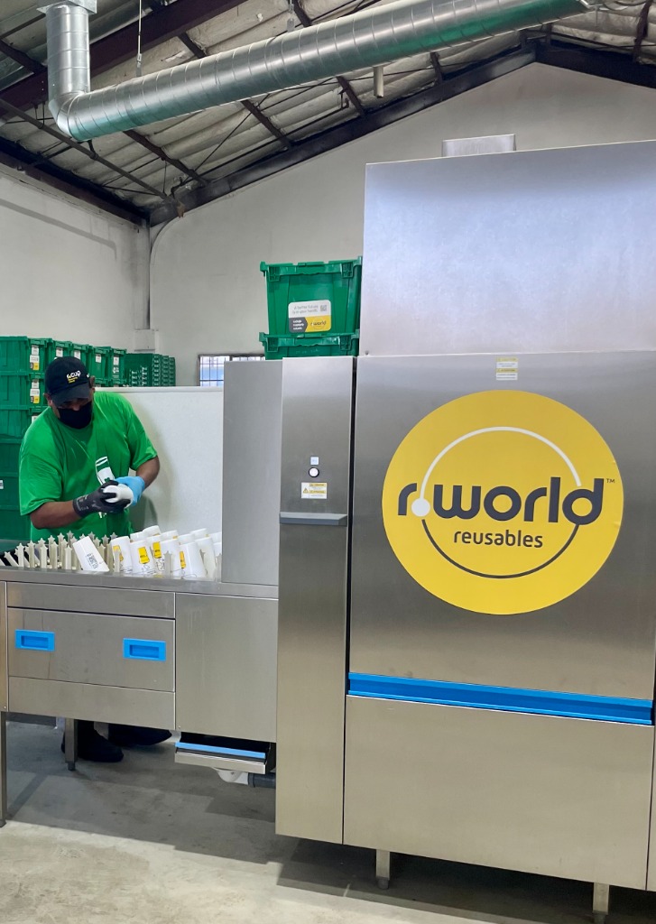 r.World staff member sanitizing reusable cups at an r.World wash center machine