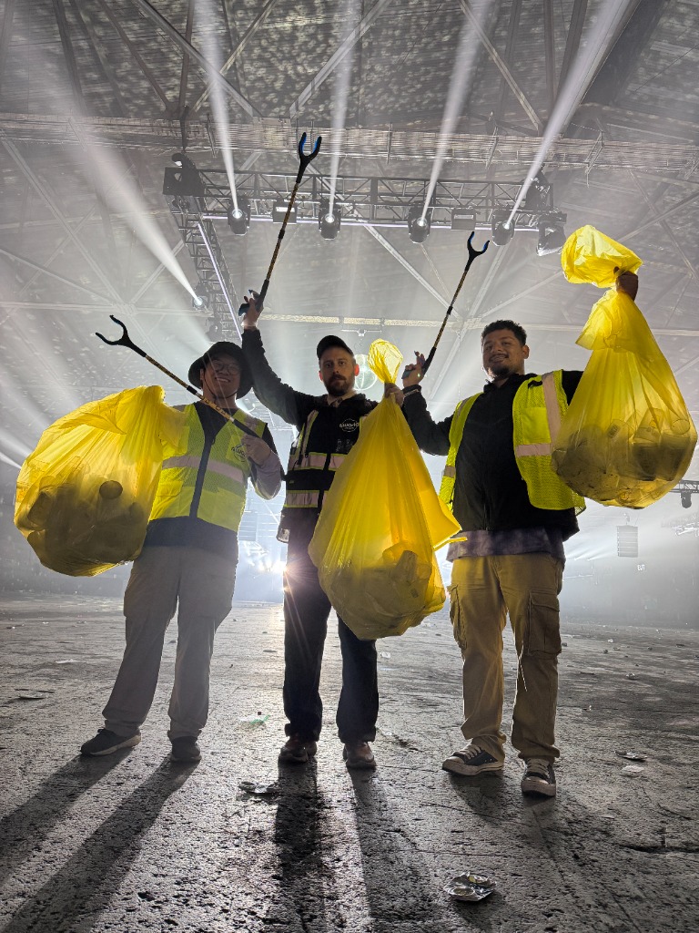 r.World operations crew holding collection bags of reusable cups at a venue